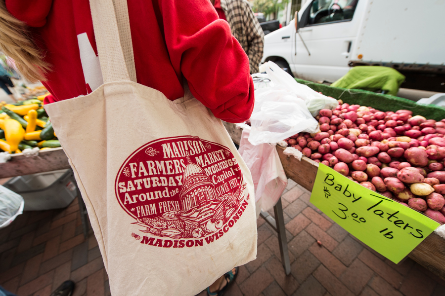 customer with madison farmer's market tote at a farmer's market stand